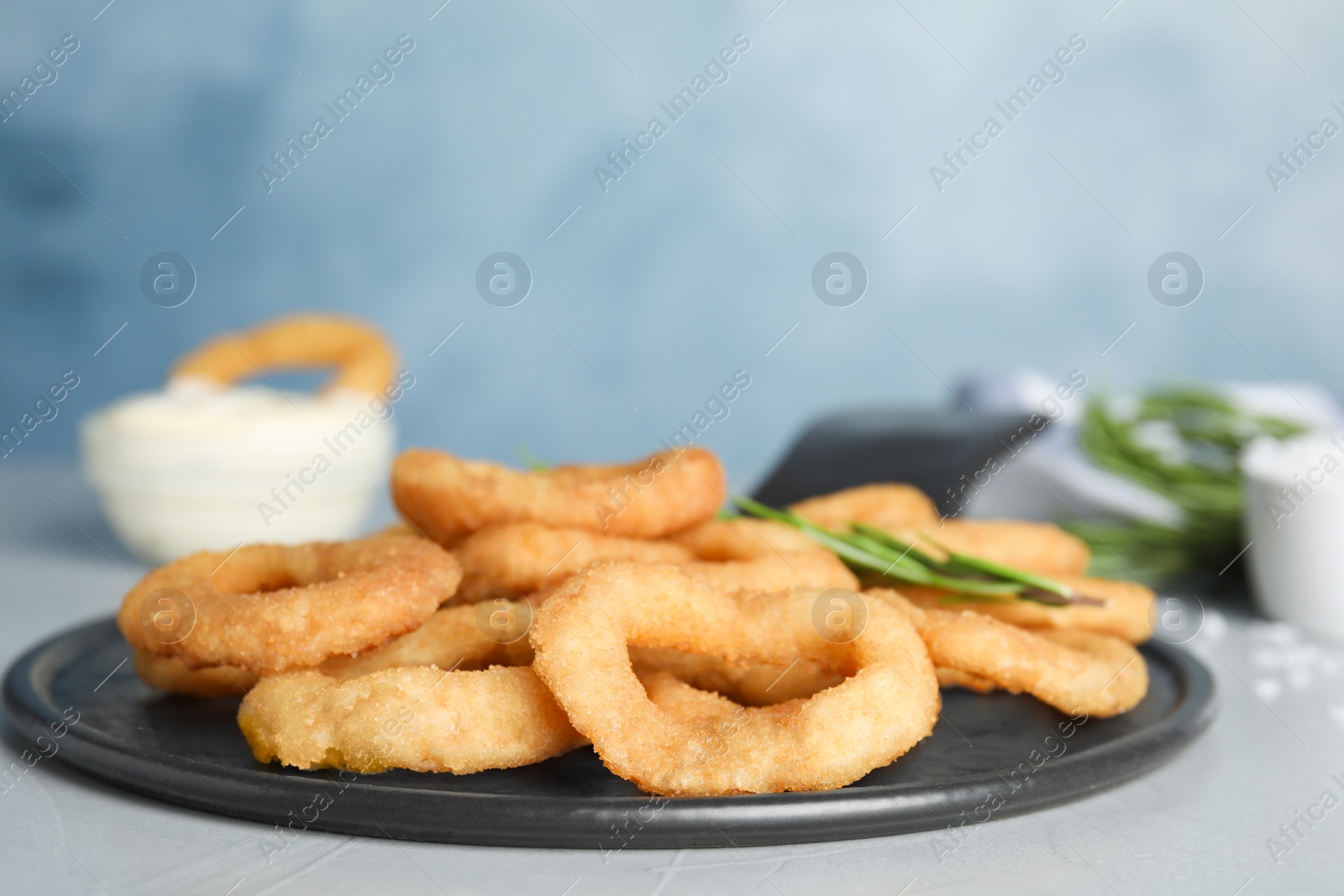 Photo of Fried onion rings served on grey table
