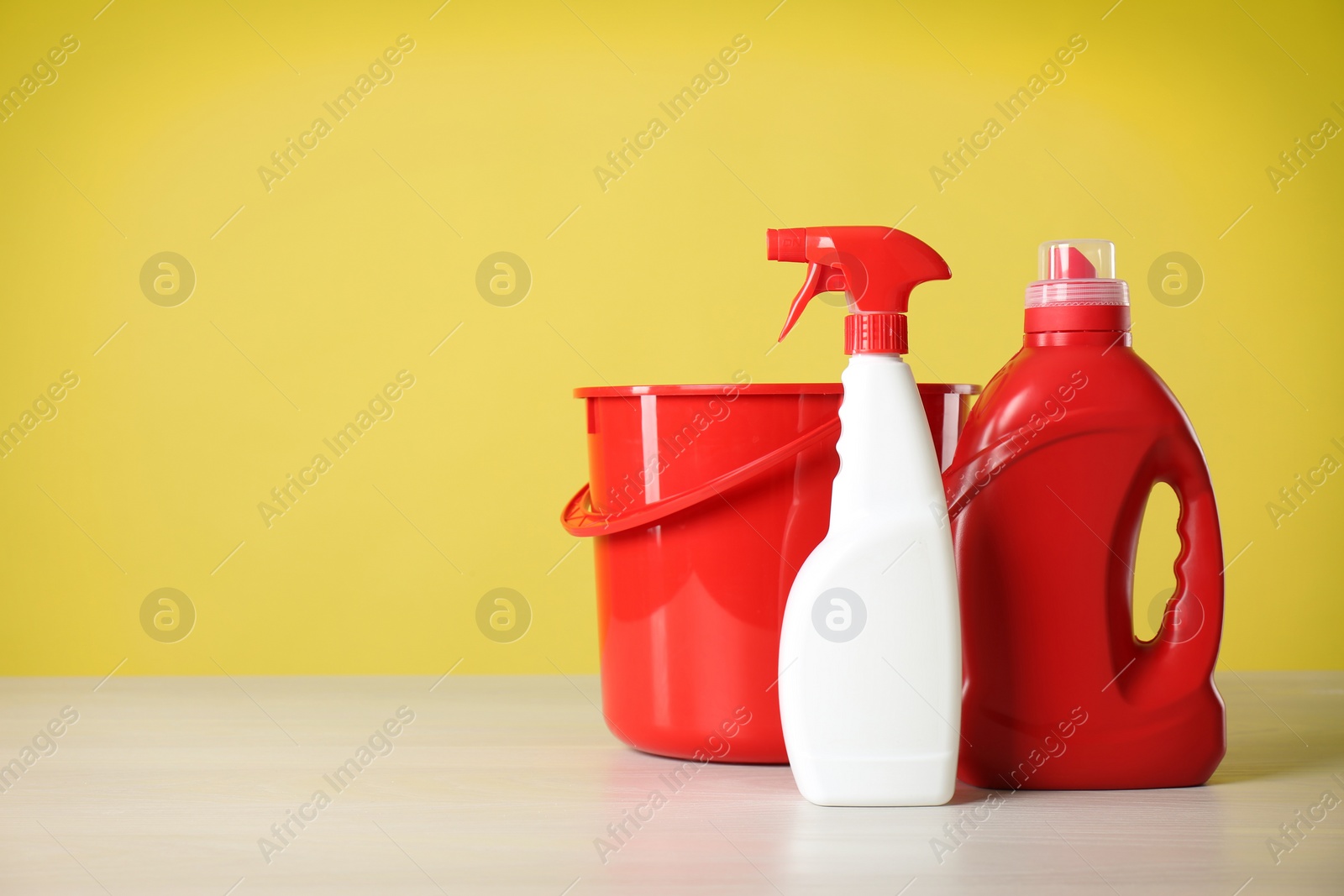 Photo of Bucket and cleaning products on grey table. Space for text