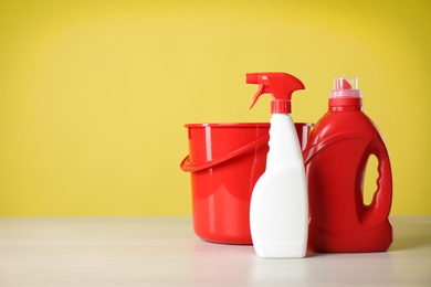 Photo of Bucket and cleaning products on grey table. Space for text