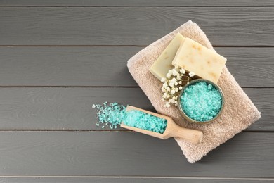 Aromatic sea salt and beautiful flowers on grey wooden table, flat lay. Space for text