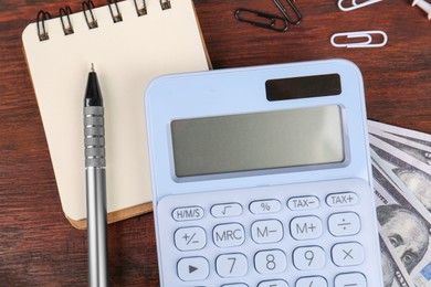 Photo of Calculator, notebook, pen, dollar banknotes and paper clips on wooden table, flat lay. Retirement concept