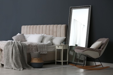 Elegant mirror near bed in stylish room interior