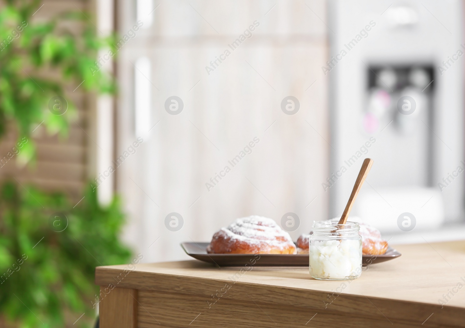 Photo of Jar with coconut oil and tasty pastry on table in kitchen. Healthy cooking