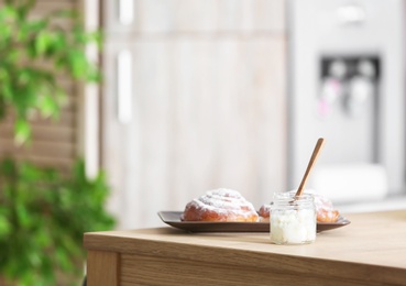 Jar with coconut oil and tasty pastry on table in kitchen. Healthy cooking