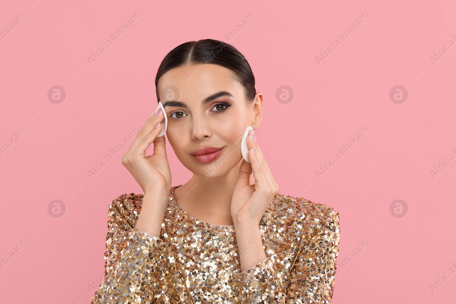 Photo of Beautiful woman removing makeup with cotton pads on pink background