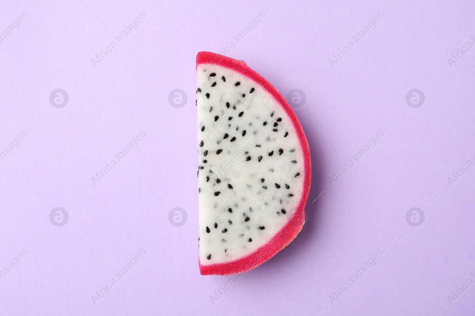 Photo of Slice of delicious dragon fruit (pitahaya) on violet background, top view