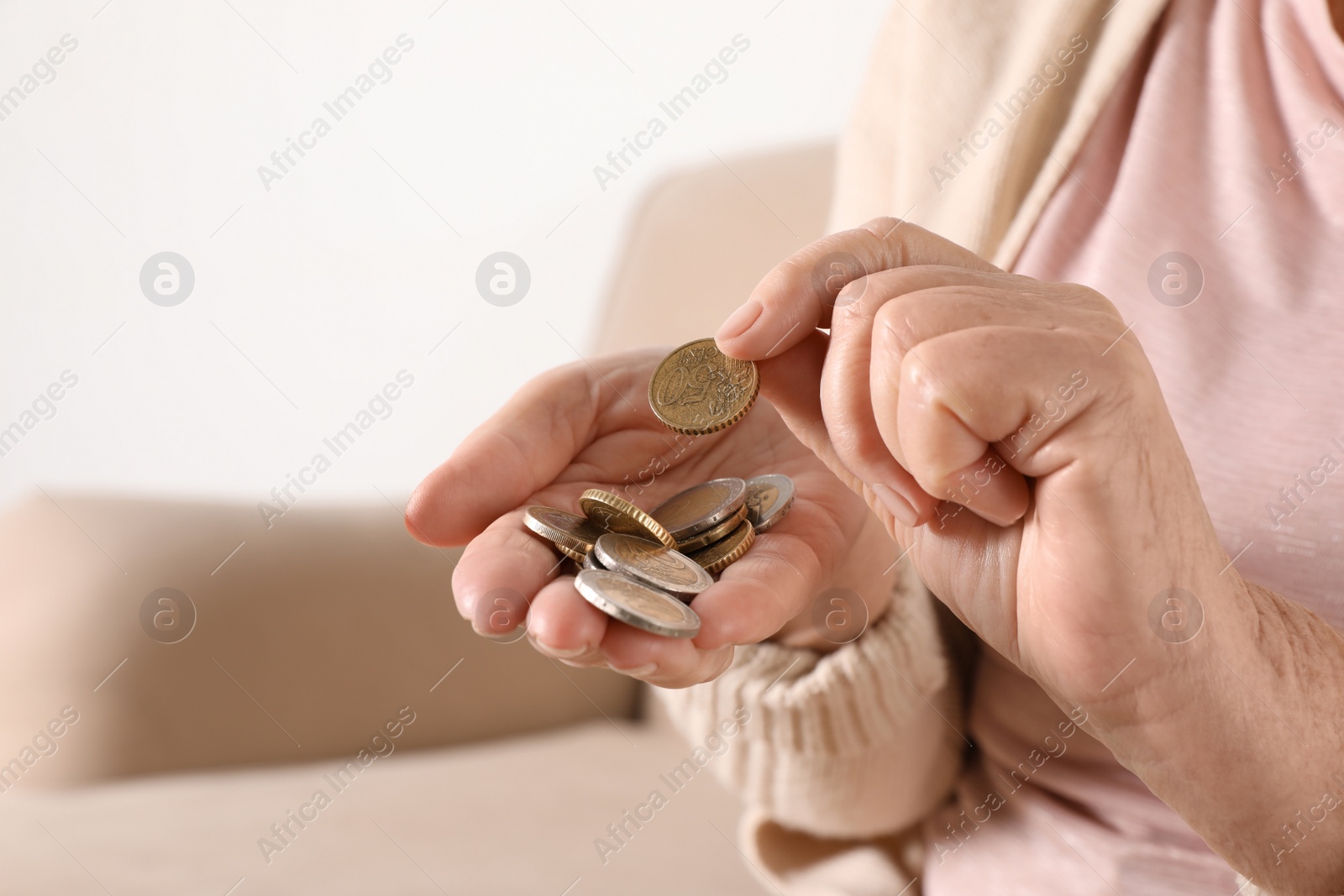 Photo of Elderly woman with pile of coins indoors, closeup