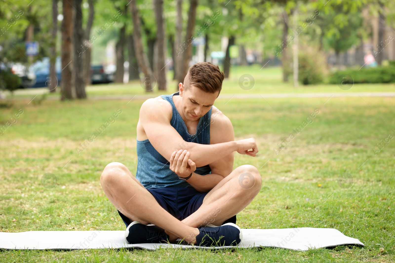 Photo of Male athlete suffering from elbow pain during training outdoors