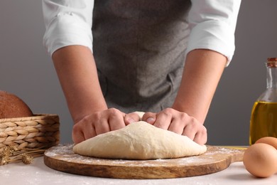 Man kneading dough at table near grey wall, closeup