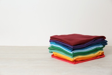 Photo of Stack of bright folded clothes on table against white background. Space for text