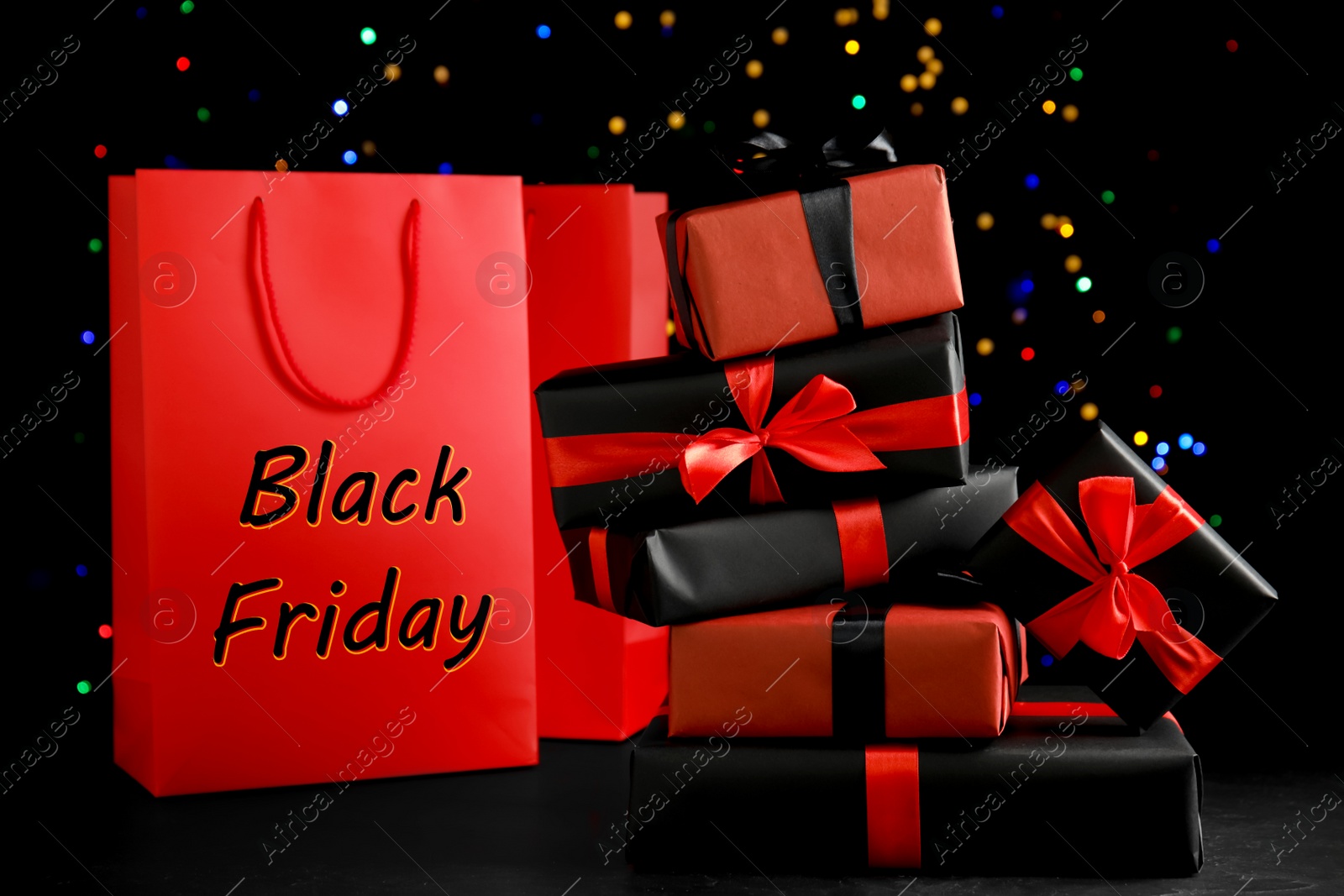 Photo of Gift boxes and paper shopping bags against blurred lights. Black Friday sale