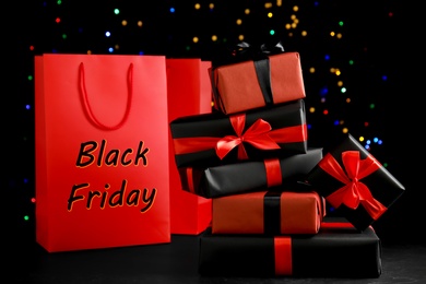 Gift boxes and paper shopping bags against blurred lights. Black Friday sale