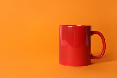 Photo of One red ceramic mug on orange background. Space for text