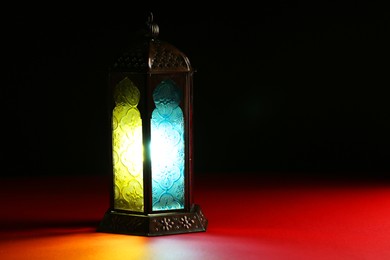 Photo of Decorative Arabic lantern on table against dark background. Space for text