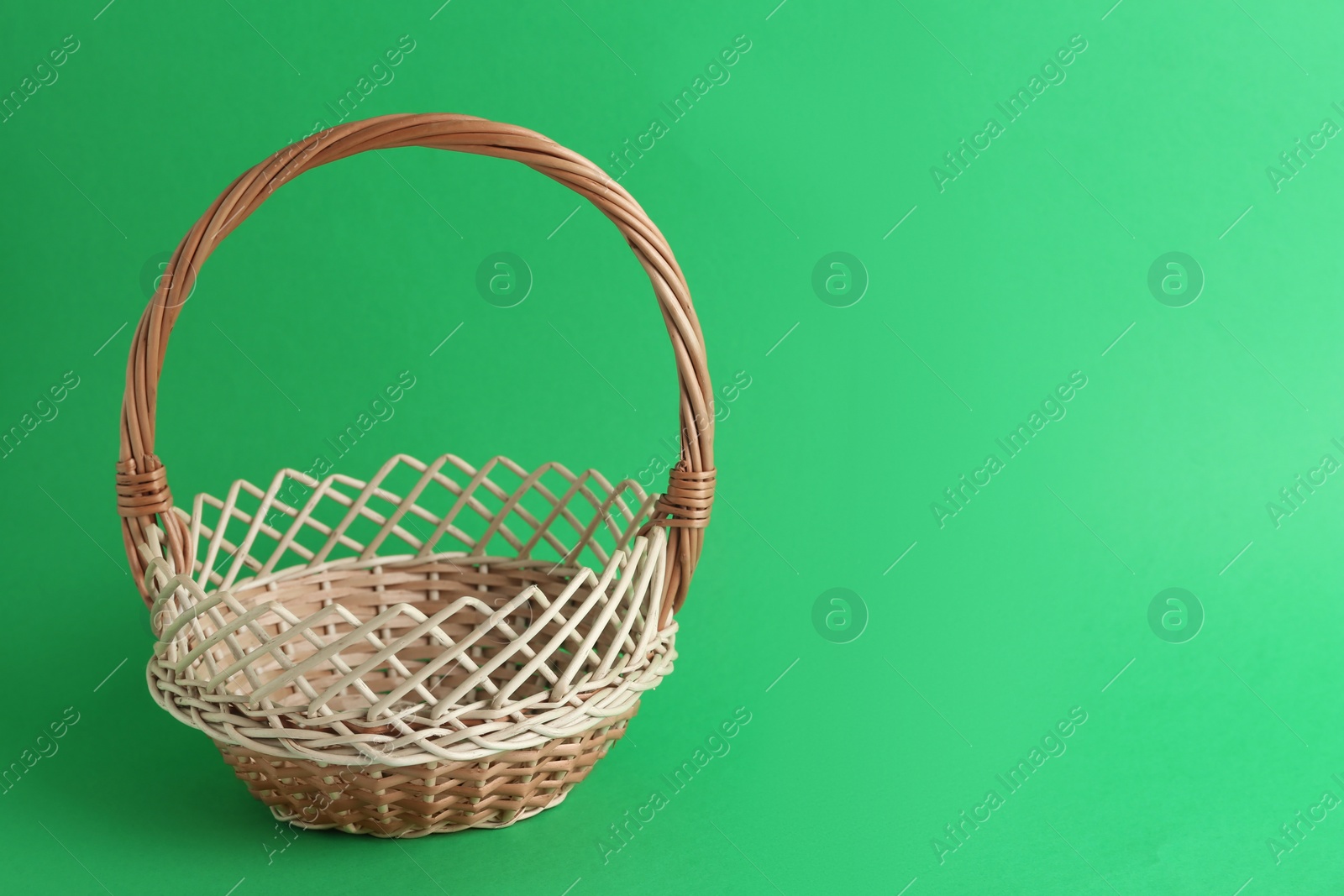 Photo of Empty wicker basket on green background, space for text. Easter item