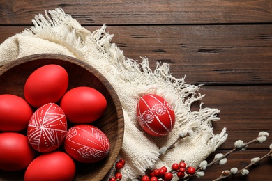 Photo of Flat lay composition with painted red Easter eggs on wooden table, space for text