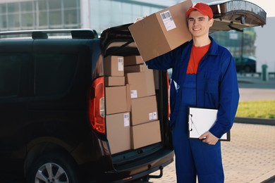 Courier with parcel and clipboard near delivery van outdoors, space for text