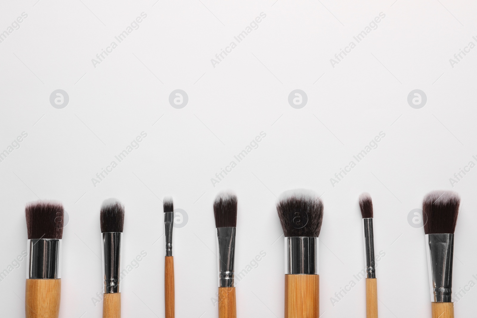 Photo of Set of makeup brushes on white background, flat lay. Space for text