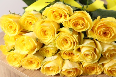 Photo of Beautiful bouquet of yellow roses on wooden table, closeup