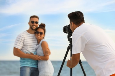 Photo of Photographer taking picture of couple with professional camera near sea