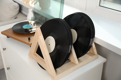 Photo of Vinyl records and player on white wooden drawer dresser indoors