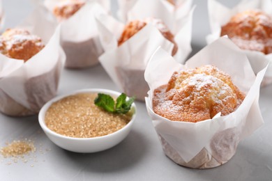 Photo of Delicious muffins with powdered sugar on grey table, closeup