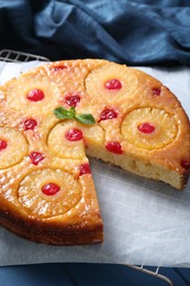 Photo of Delicious cut pineapple pie with cherry on blue table