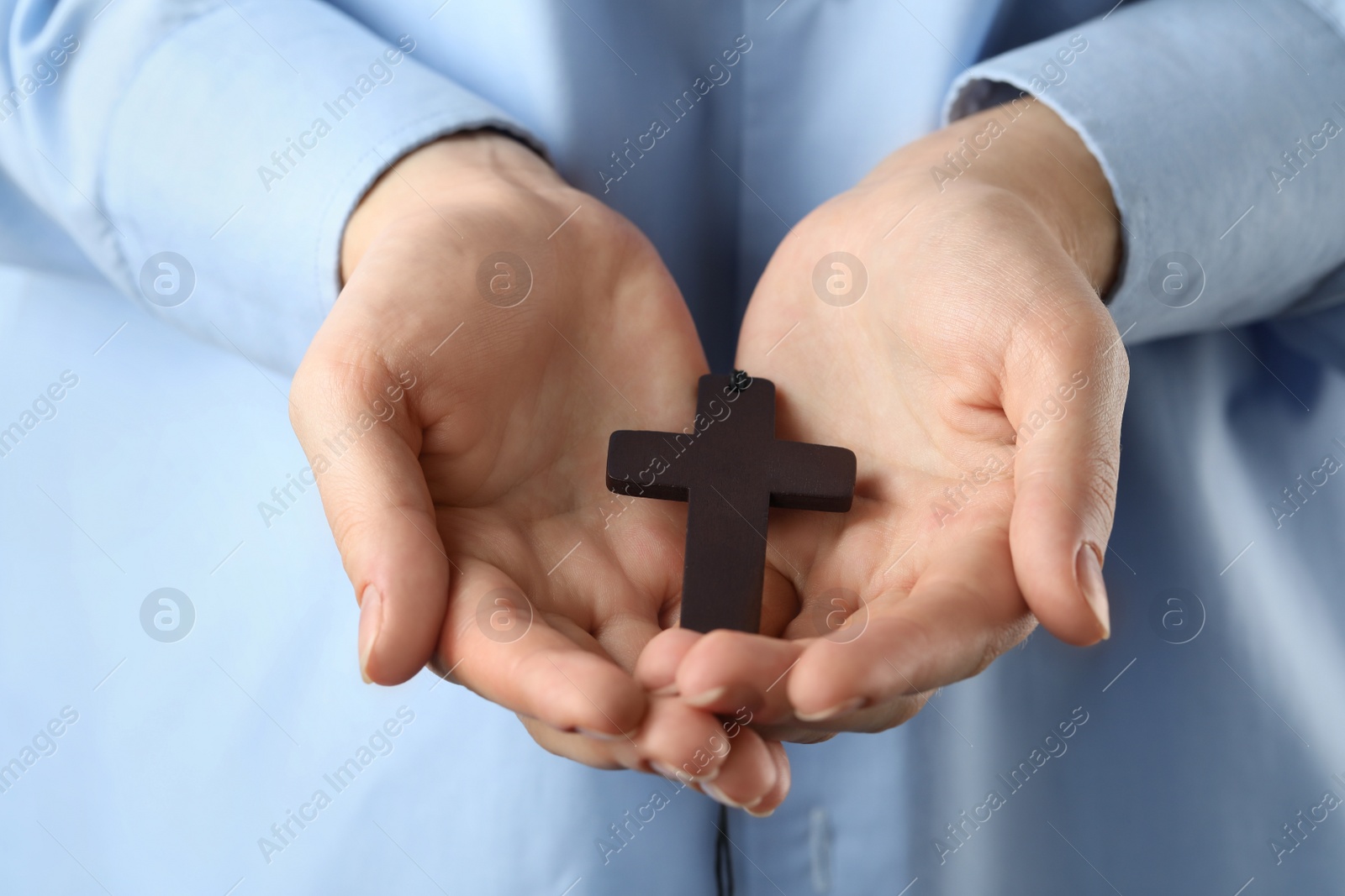 Photo of Woman holding wooden Christian cross, closeup view