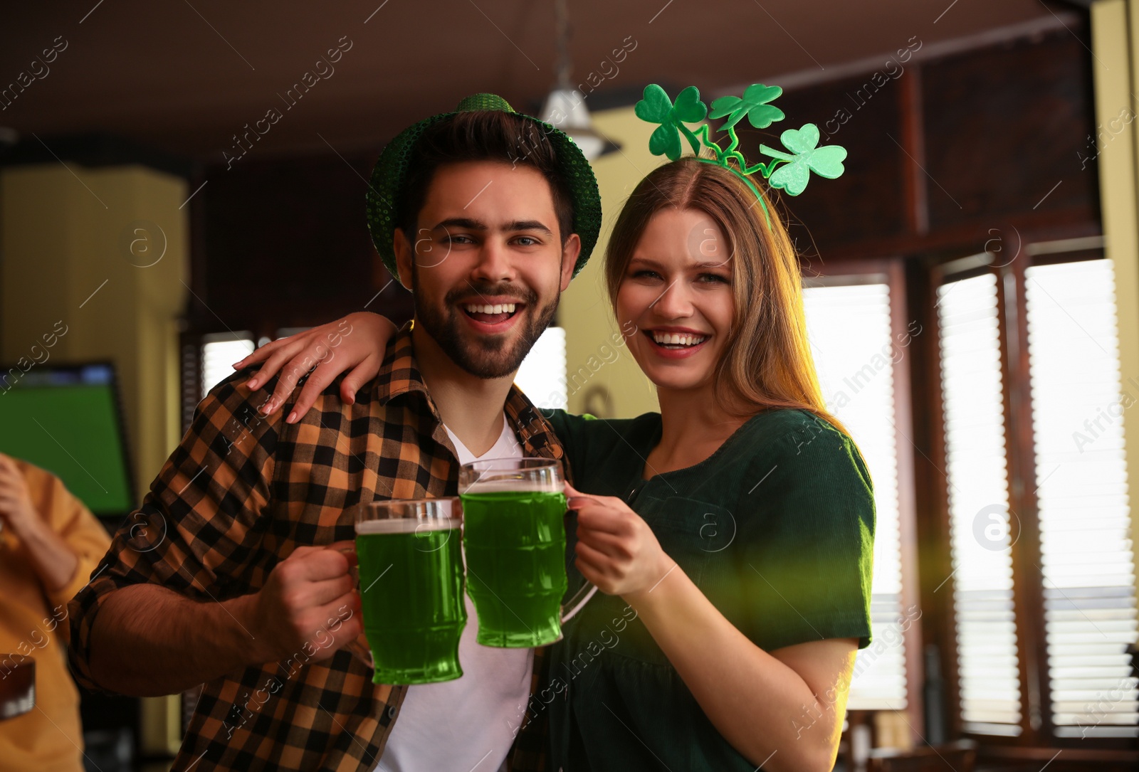 Photo of Young man and woman toasting with green beer in pub. St. Patrick's Day celebration