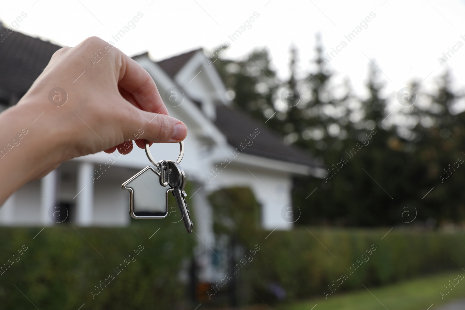 Photo of Woman holding house keys outdoors, closeup with space for text. Real estate agent