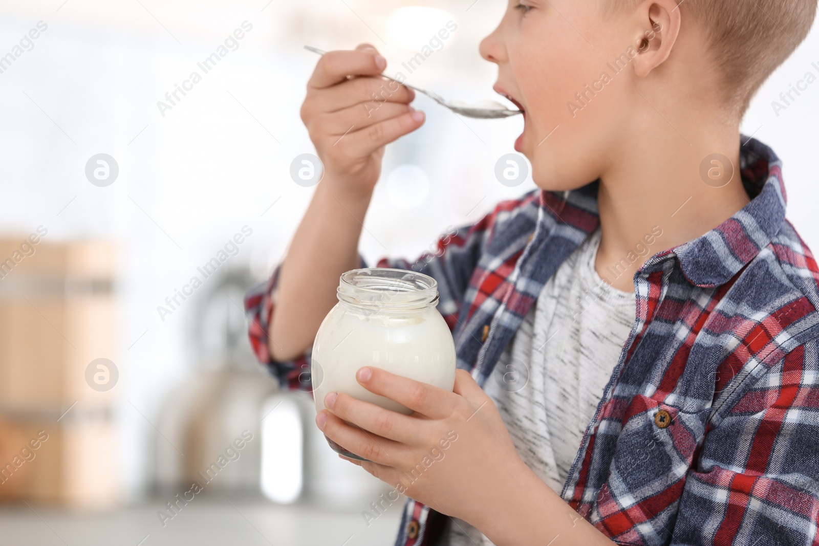 Photo of Little boy with yogurt on blurred background, closeup