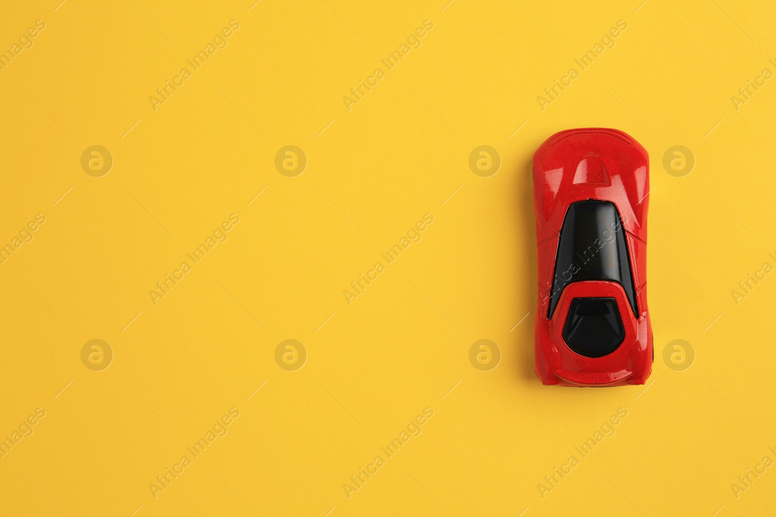 Photo of One red car on yellow background, top view with space for text. Children`s toy