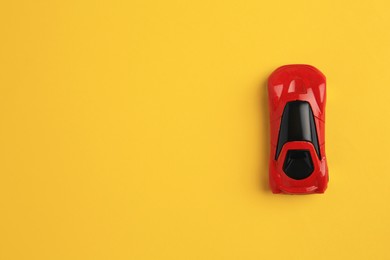 One red car on yellow background, top view with space for text. Children`s toy