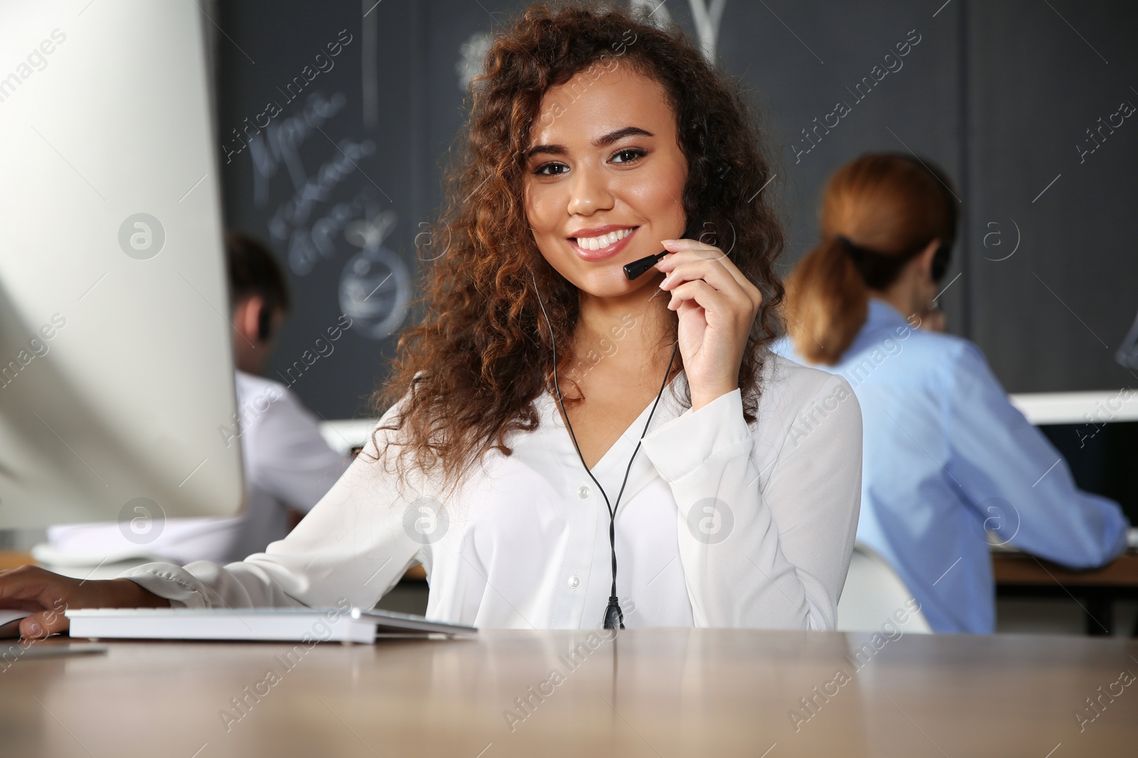 Photo of African-American technical support operator with headset at workplace