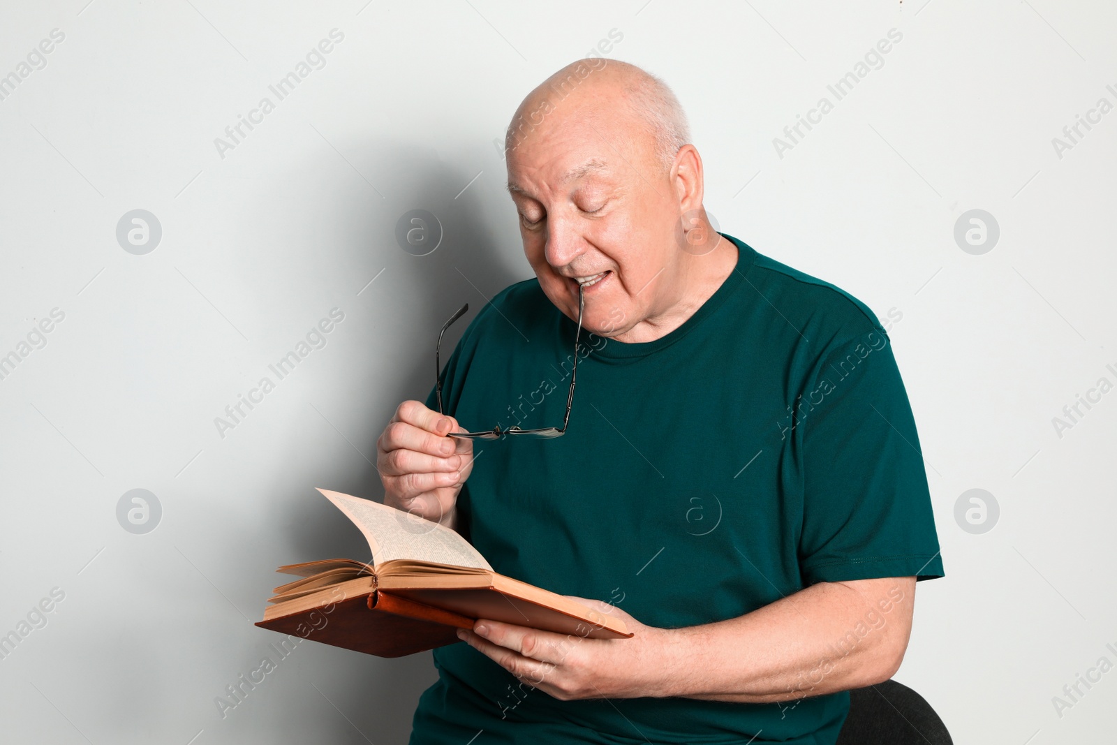 Photo of Portrait of senior man with glasses reading book on light background