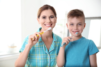 Photo of Portrait of mother and her son with toothbrushes in bathroom. Personal hygiene