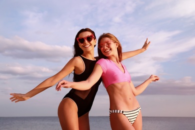 Young woman in bikini with girlfriend on beach. Lovely couple