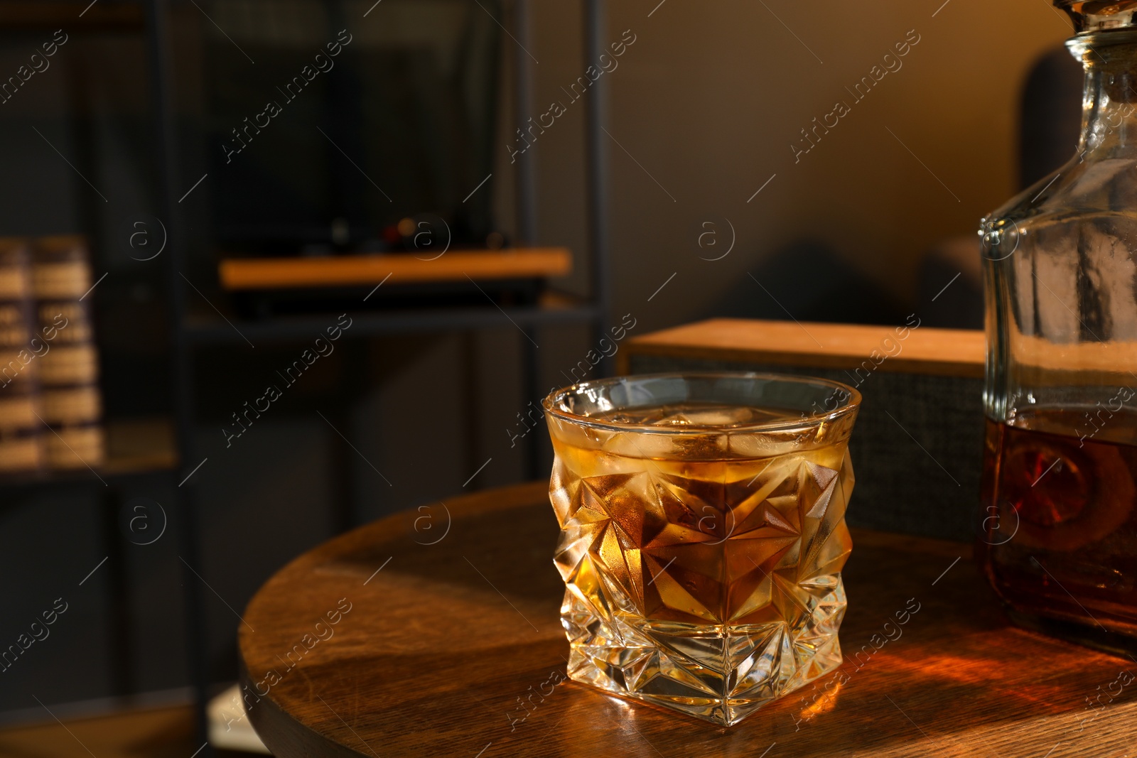 Photo of Bottle and glass of whiskey on wooden table in room, space for text. Relax at home