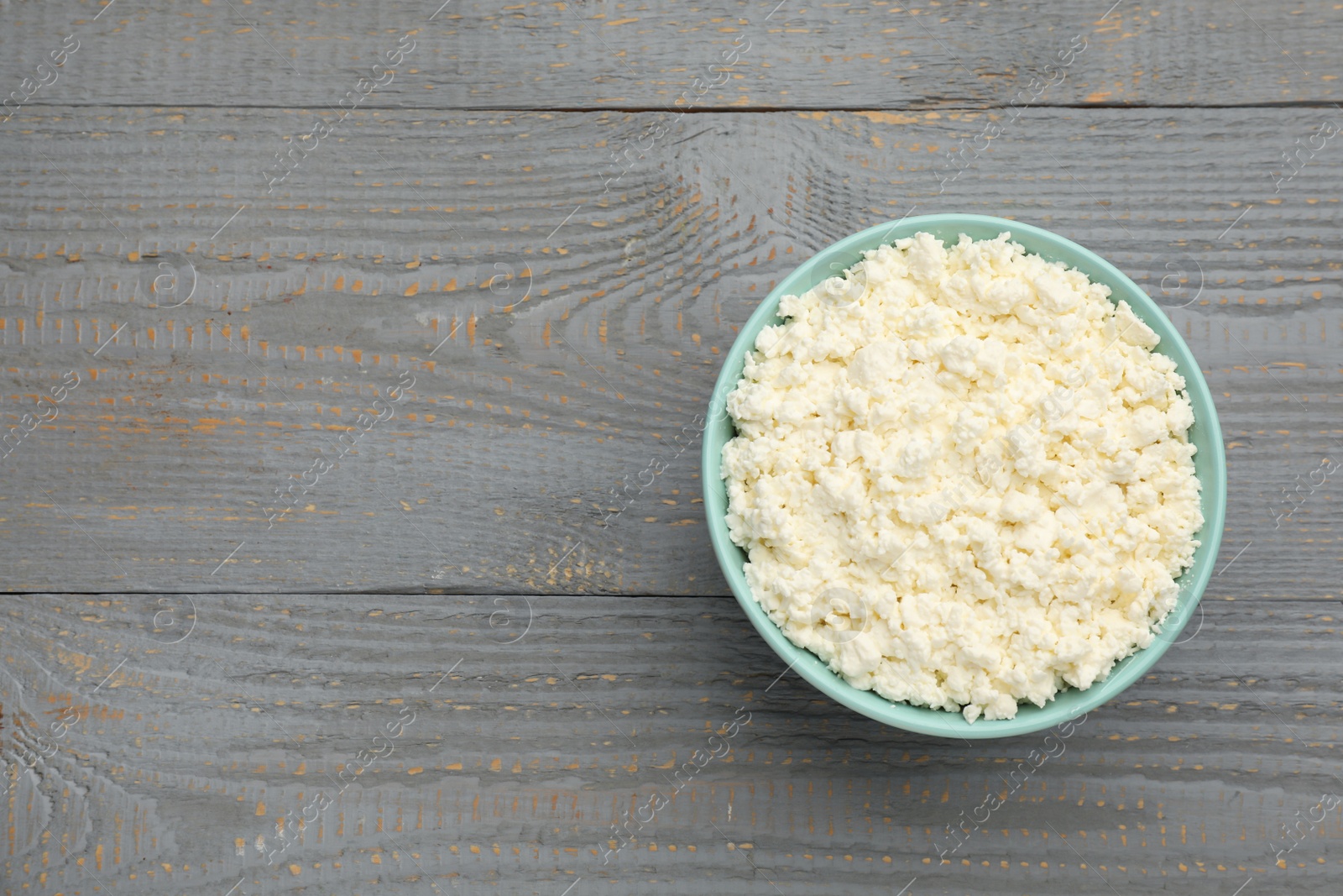 Photo of Delicious fresh cottage cheese on grey wooden table, top view. Space for text