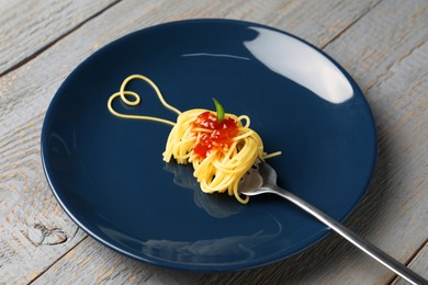 Photo of Heart made with spaghetti and fork on grey wooden table