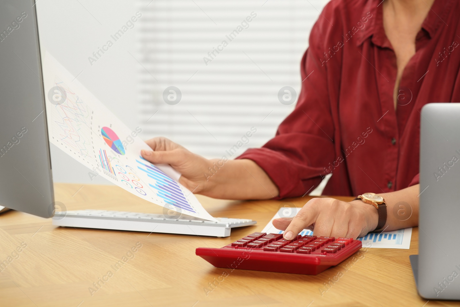 Photo of Accountant using calculator at wooden desk in office, closeup