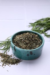 Photo of Dry and fresh tarragon on white tiled table