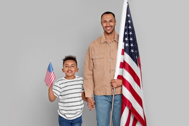 Photo of 4th of July - Independence Day of USA. Happy man and his son with American flags on light grey background