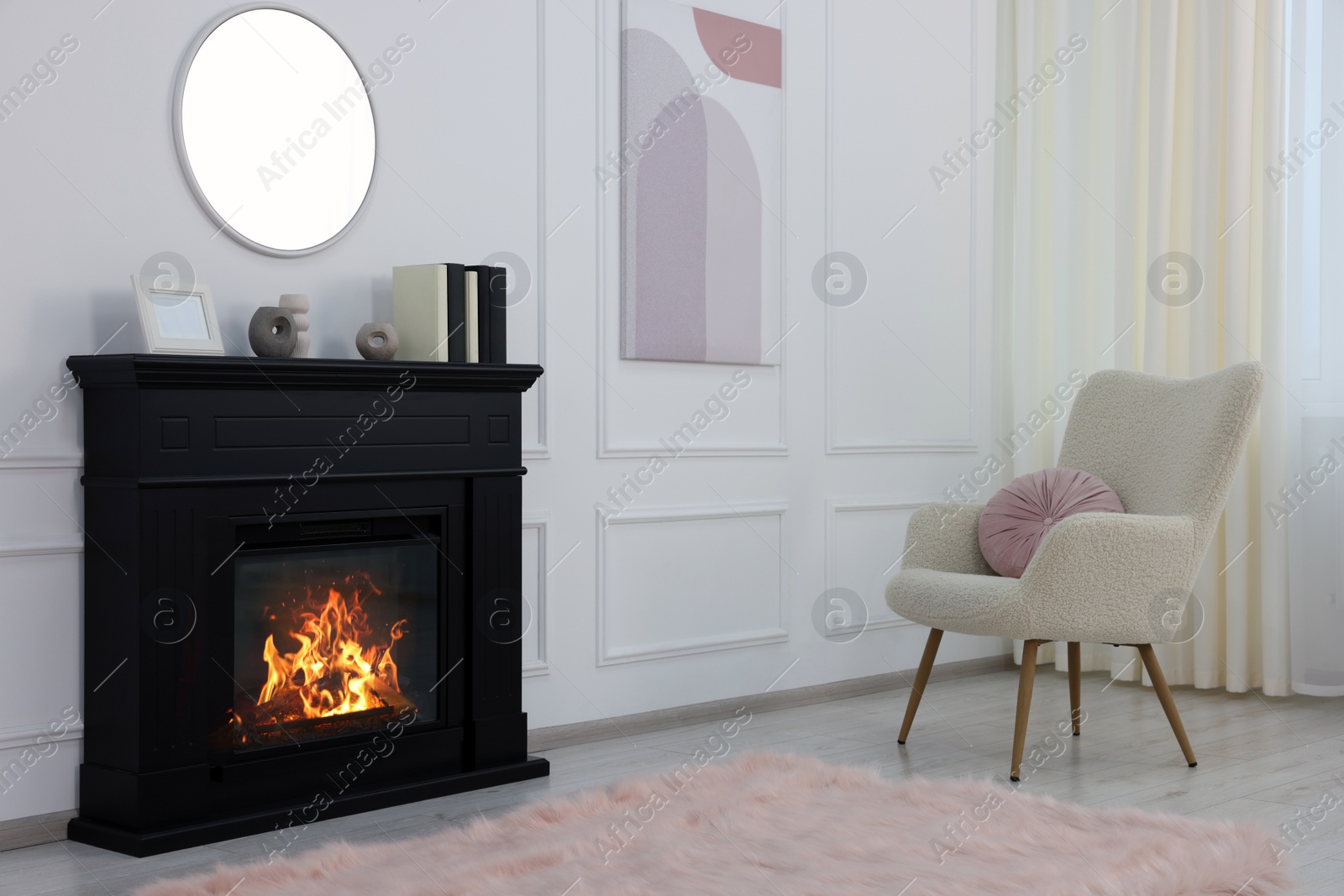 Photo of Black stylish fireplace near soft armchair in cosy living room