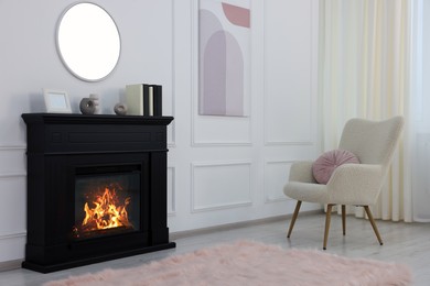 Black stylish fireplace near soft armchair in cosy living room