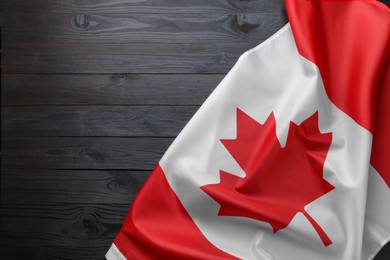 Flag of Canada on dark wooden table, top view. Space for text