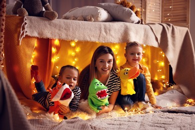 Photo of Mother and her children playing with toys in play tent at home