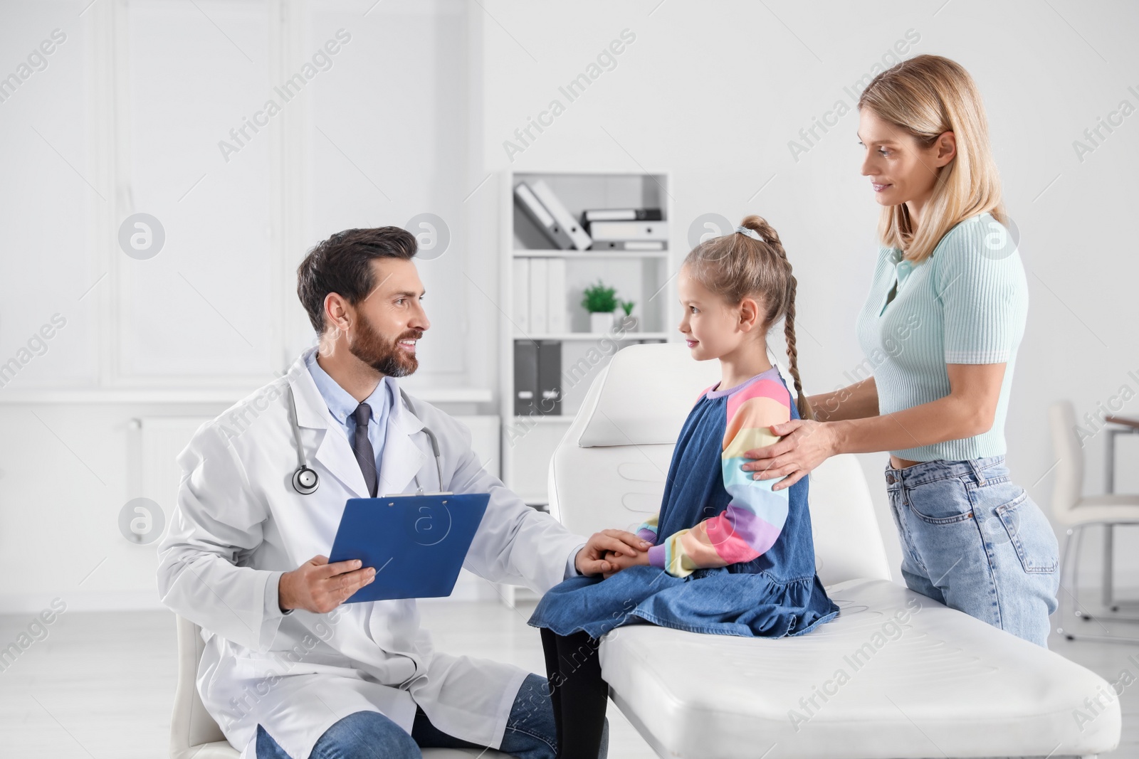 Photo of Mother and daughter having appointment with doctor. Pediatrician consulting patient in clinic