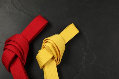 Photo of Colorful karate belts on gray background, flat lay. Space for text