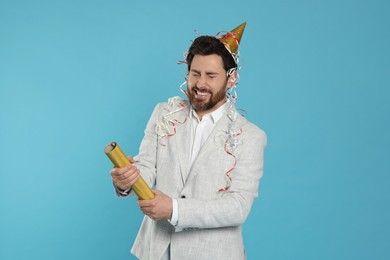 Photo of Emotional man with party popper on light blue background